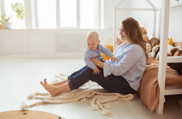 Jeune mère assise avec bébé, regardant l'enfant avec amour et soin