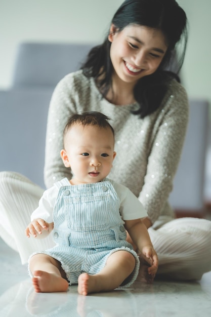 Jeune mère assise sur le sol pieds nus avec un tout-petit à la maison