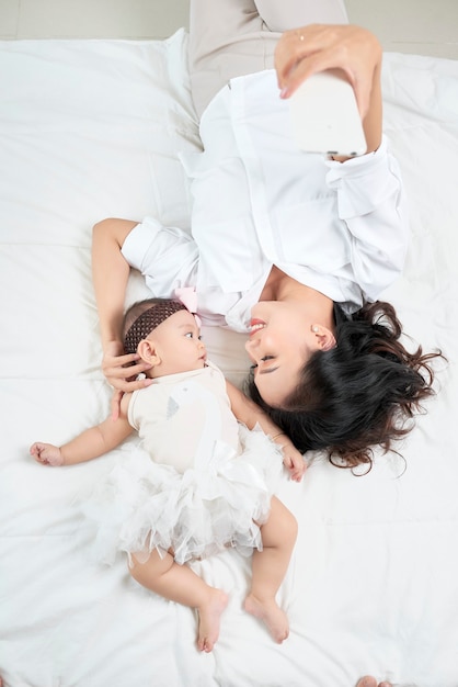 Jeune mère et bébé mignon sur le lit à la maison