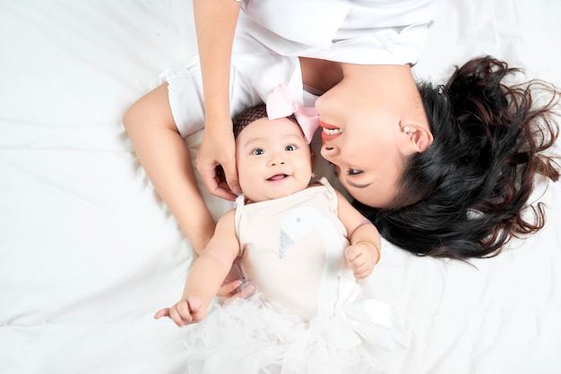 Jeune mère et bébé mignon sur le lit à la maison