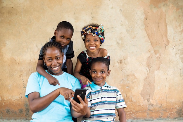 Photo jeune mère célibataire africaine heureuse et bonne s'amusant avec ses enfants et prenant des photos de selfie sur l'appareil photo du smartphone.