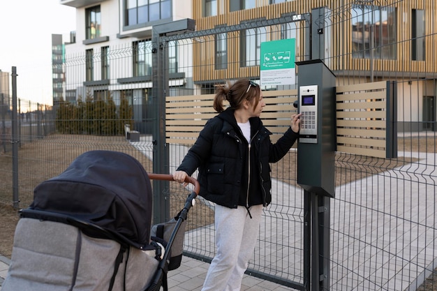 Une jeune mère en congé de maternité retourne dans la cour sécurisée avec un landau avec son bébé