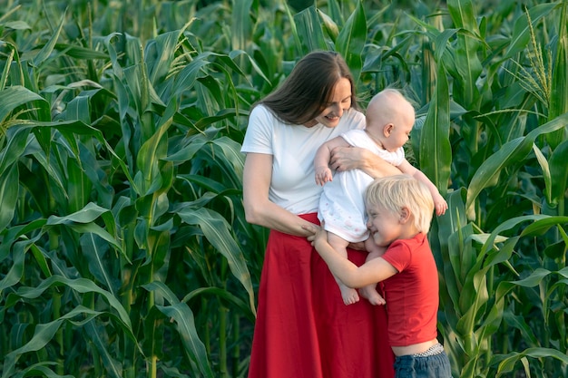 Jeune mère avec deux enfants sur fond de verdure de maïs Reste avec la campagne des enfants
