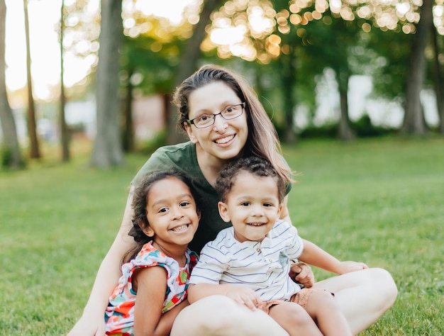 Une jeune mère du millénaire et des enfants de races mixtes diverses au parc s'amusent en famille.