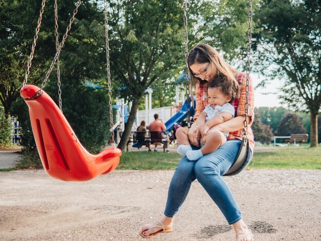 Une jeune mère du millénaire et un tout-petit garçon diversifié se lient à l'extérieur dans un parc local