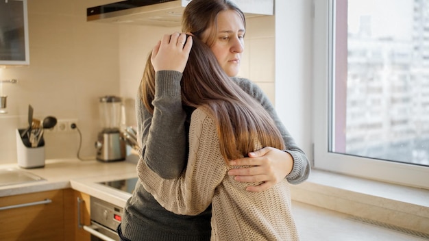 Photo jeune mère embrassant et consolant sa fille en parlant de problèmes et de dépression