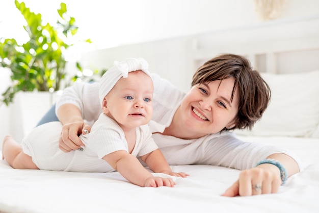 une jeune mère embrasse doucement son enfant en l'embrassant et en l'admirant une mère de famille heureuse et son bébé sur le lit jouant et s'amusant l'amour et les soins maternels une maman heureuse en congé de maternité