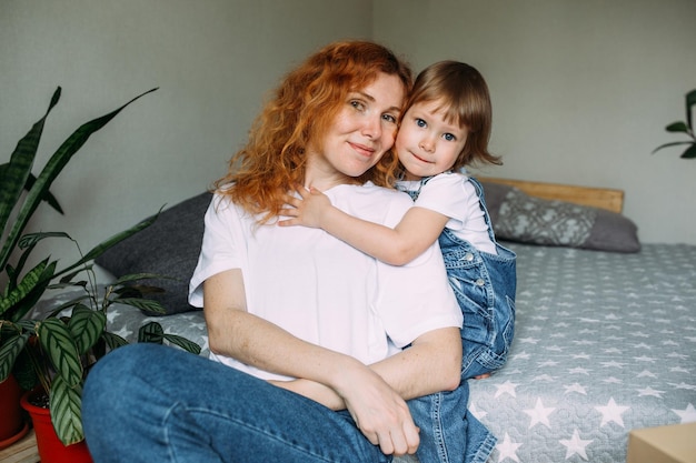 La jeune mère et l'enfant s'amusent et se moquent à la maison sur le lit.