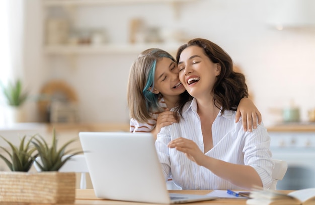 Jeune mère avec enfant travaillant sur l'ordinateur. Famille à la maison. Travail à distance.