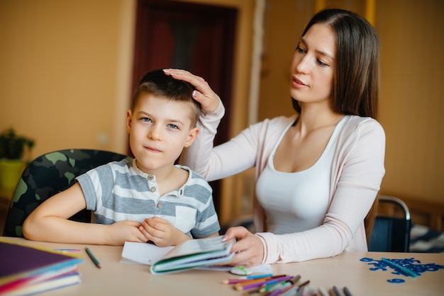 Une jeune mère fait ses devoirs avec son fils à la maison.