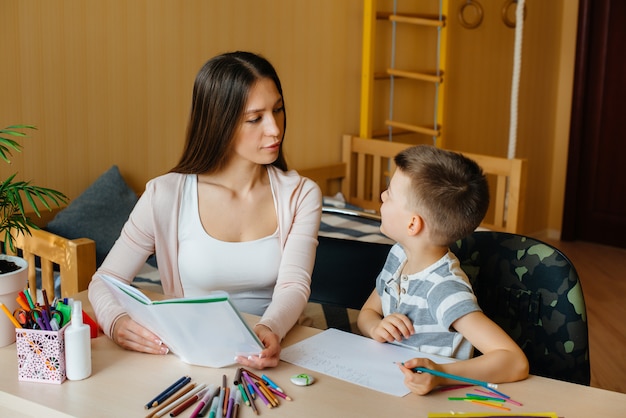 Une jeune mère fait ses devoirs avec son fils à la maison