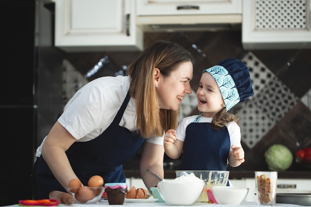 Jeune mère et fille dans la cuisine préparant des cupcakes et souriant, riant.