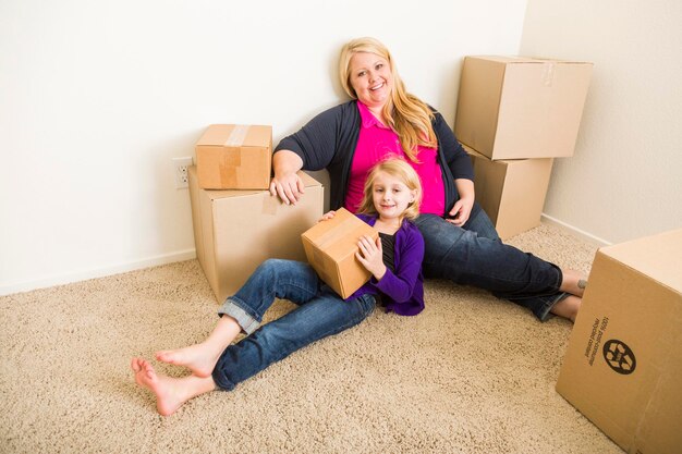 Jeune mère et fille dans une pièce vide avec des boîtes de déménagement
