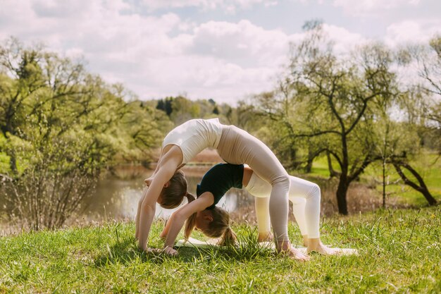 Jeune mère et fille faisant du yoga en plein air dans le parc