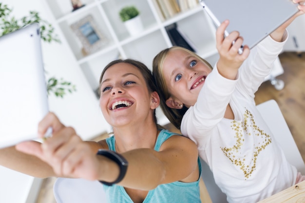 Jeune mère et fille jouent avec une tablette numérique à la maison.