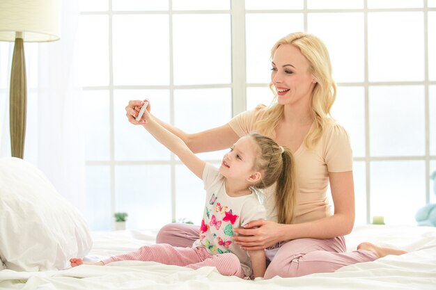 Jeune mère et fille matin sur lit à l'intérieur