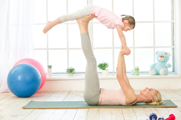 Jeune mère et fille s'exercent ensemble à l'intérieur