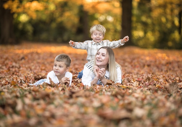 Une jeune mère heureuse et deux frères se promènent dans la forêt d'automne Activité de plein air d'automne pour la famille avec des enfants Joyeuse fête des mères