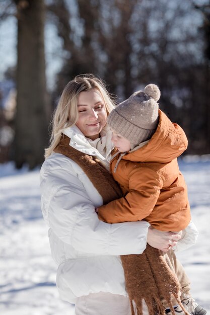 Une jeune mère heureuse avec son fils se promènent dans le parc d'hiver Portrait d'une famille heureuse en plein air