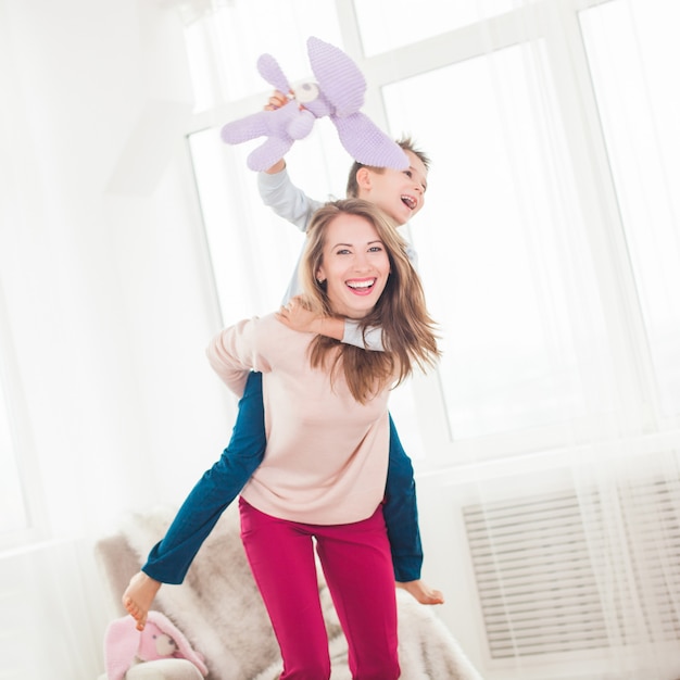 Jeune mère jouant à des jeux actifs avec son fils. Famille joyeuse à l'intérieur s'amuser.