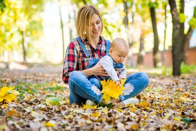 jeune mère jouant avec son bébé dans le parc à l'automne