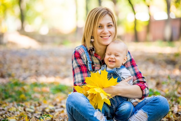 jeune mère jouant avec son bébé dans le parc à l'automne