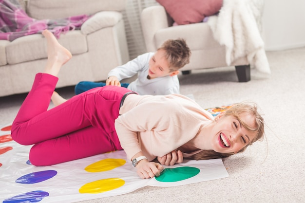 Jeune mère jouant twister avec son fils. Famille joyeuse à l'intérieur. Famille heureuse, jouer ensemble