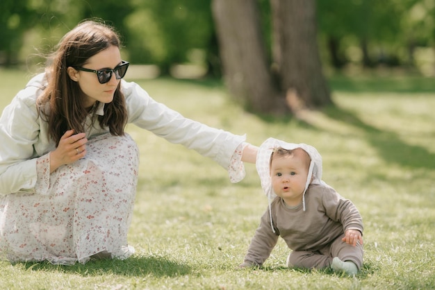 Une jeune mère joue avec sa fille de mois sur l'herbe