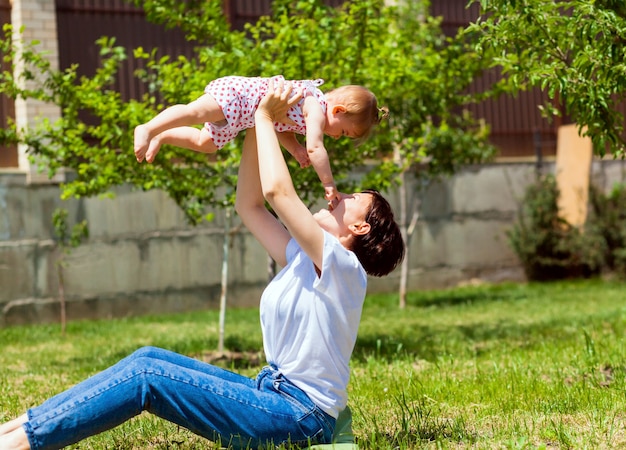 Jeune mère joue avec son bébé sur l'herbe dans le parc. Maman et bébé