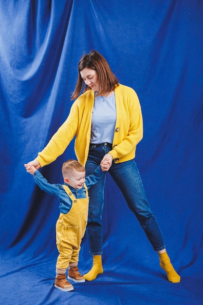 Une jeune mère joue avec son enfant sur fond bleu Relation familiale avec l'enfant Élever un enfant jouant avec un enfant