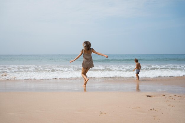 Photo une jeune mère joue avec son fils dans les vagues de la mer au bord de la mer