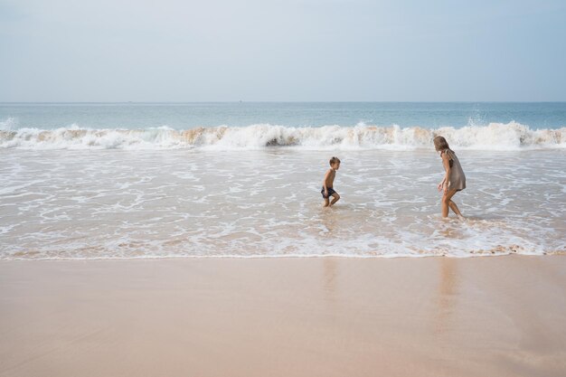 Une jeune mère joue avec son fils dans les vagues de la mer.