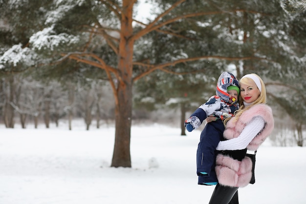 Une jeune mère marche un jour d'hiver avec un bébé dans ses bras dans le parc