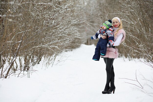 Une jeune mère marche un jour d'hiver avec un bébé dans ses bras dans le parc