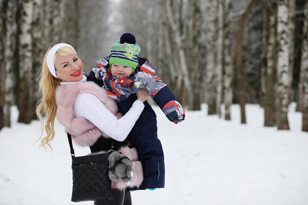 Une jeune mère marche un jour d'hiver avec un bébé dans ses bras dans le parc