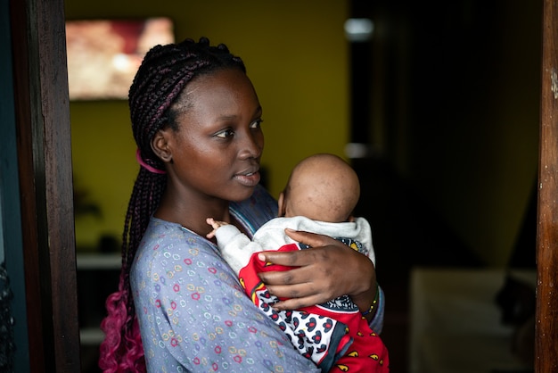 Photo jeune mère noire tenant bébé