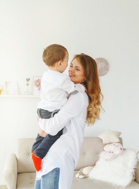 Une jeune mère avec un petit fils mignon s'amuse dans un salon confortable et lumineux