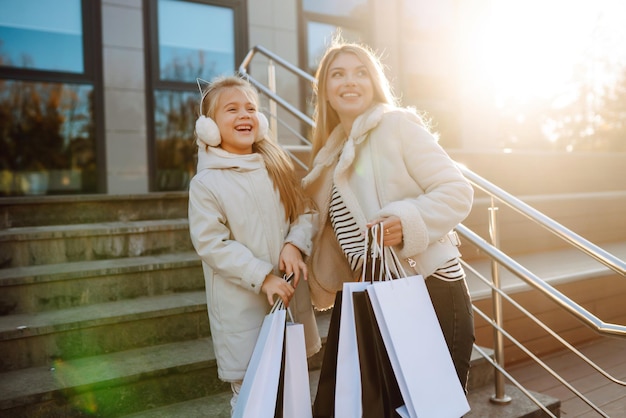 Une jeune mère et une petite fille avec des sacs de shopping après avoir fait leurs courses.