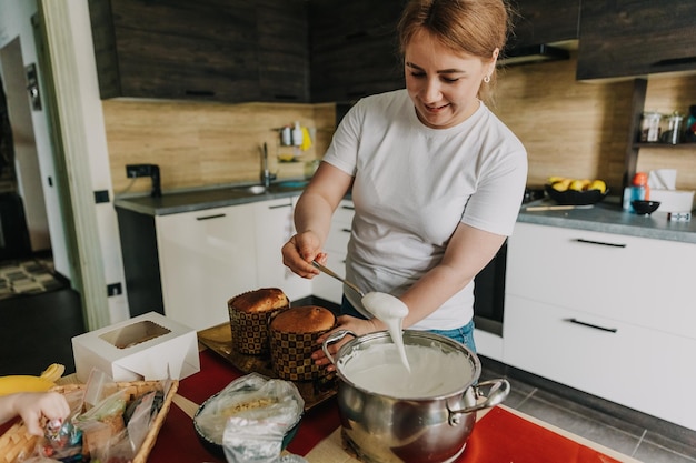 La jeune mère pétrit la pâte pour faire cuire des gâteaux festifs de Pâques