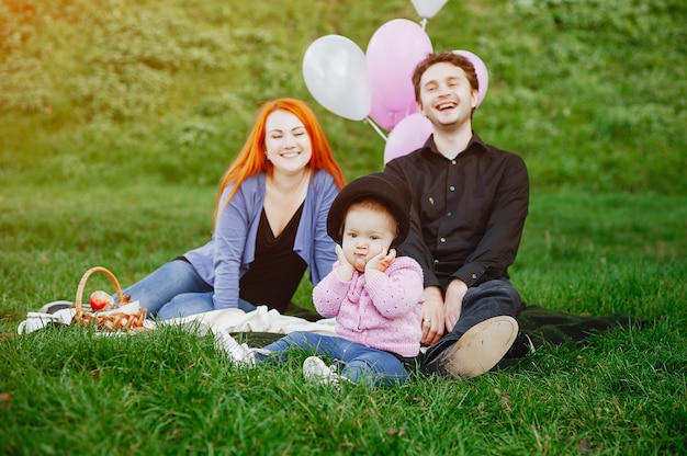 Une jeune mère rousse assis dans le parc avec son mari et leur petite fille