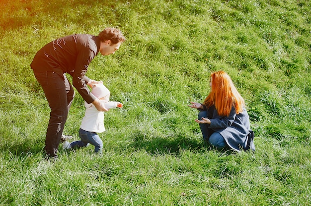 Une jeune mère rousse joue dans le parc avec son mari et leur petite fille