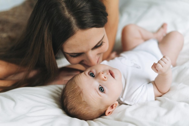 Jeune mère s'amusant avec une jolie petite fille sur le lit, les tons naturels aiment l'émotion