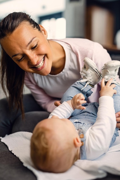 Photo jeune mère s'amusant avec son petit garçon tout en jouant avec lui du canapé à la maison