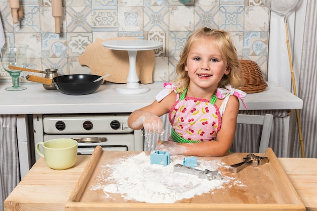 Jeune mère et sa fille cuisinent dans la cuisine dans de beaux tabliers