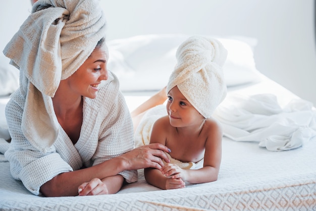 Une jeune mère avec sa fille a une journée de beauté à l'intérieur dans une salle blanche.