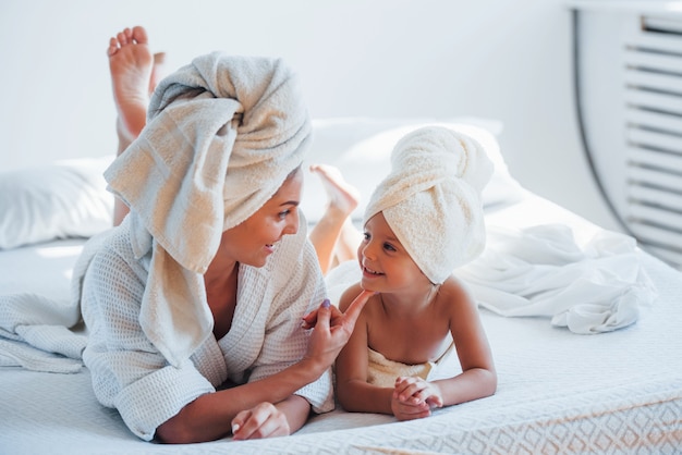 Une jeune mère avec sa fille a une journée de beauté à l'intérieur dans une salle blanche.