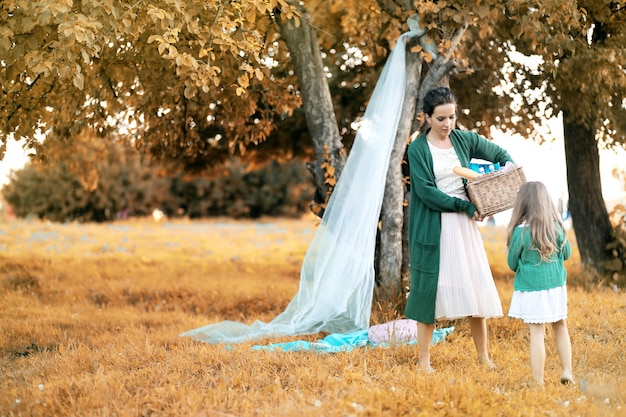 Jeune mère avec sa fille lors d'un pique-nique dans le parc en automne