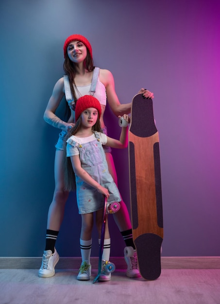 Une jeune mère avec sa fille sur une planche à roulettes et un longboard