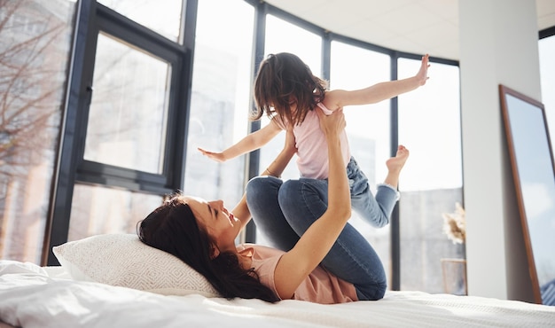 Une jeune mère avec sa fille s'amuse le week-end ensemble au lit