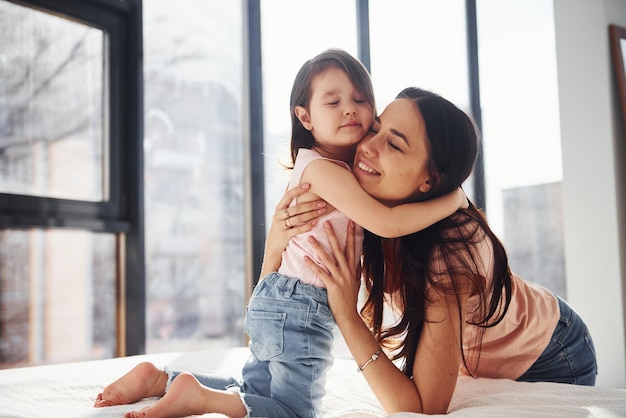 Jeune mère avec sa fille s'embrassant sur le lit